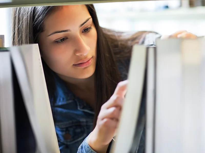 Student browsing books in a research library