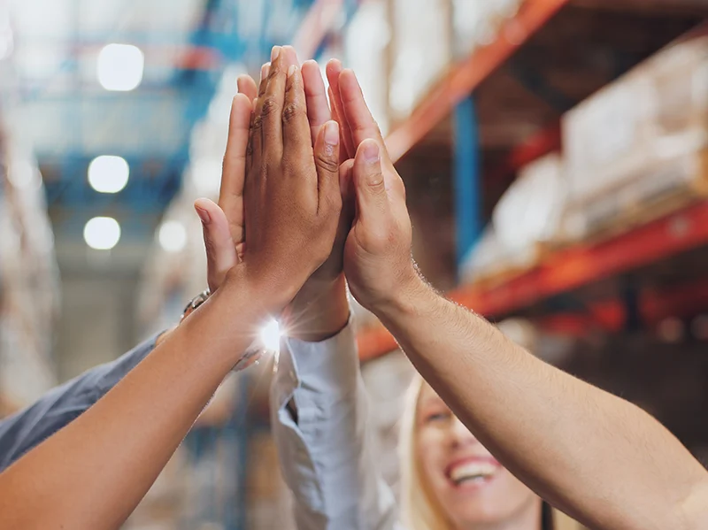Team members high-fiving in a warehouse innovation hub